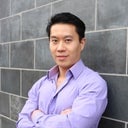 Dr Tsai 1 Portrait of Dr. Tsai. He is wearing a lavendar button up shirt and leaning against a brick wall with arms folded.
